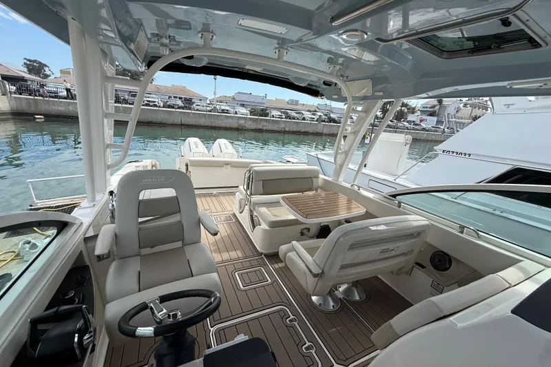 Slide: The Image of 2023 Boston Whaler 320 Vantage boat interior with seating and steering wheel, docked at marina. - 19