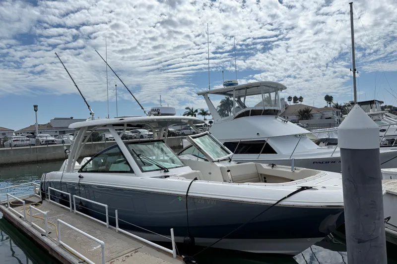 Slide: The Image of 2023 Boston Whaler 320 Vantage docked at marina under cloudy sky. - 2