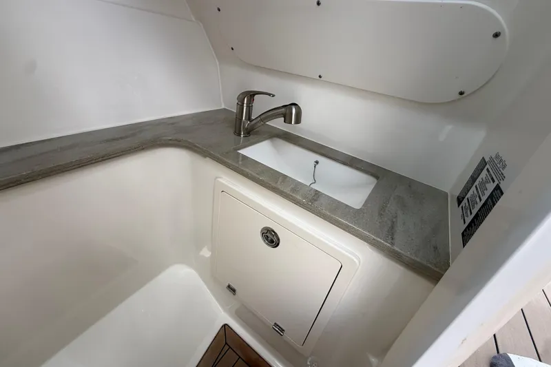 Slide: The Image of 2023 Boston Whaler 320 Vantage interior sink area with modern faucet and storage compartment. - 22