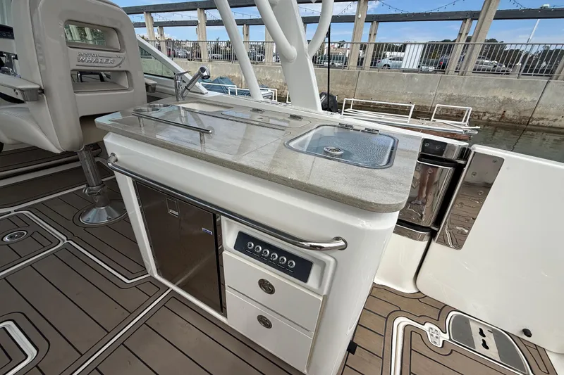 Slide: The Image of 2023 Boston Whaler 320 Vantage boat interior with kitchenette and seating. - 9