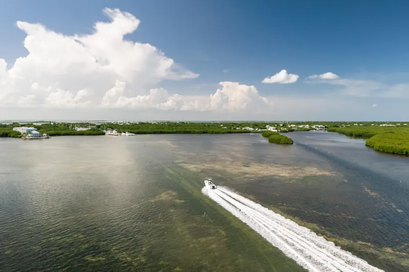 Slide: The Image of Aerial view of a 2013 Deep Impact 33 boat speeding through scenic coastal waters. - 32