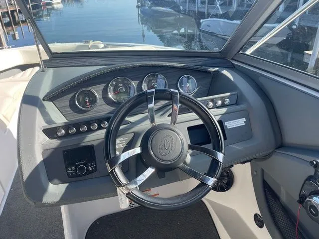 Slide: The Image of Steering wheel and dashboard of a 2016 Cobalt R3 boat, docked by the water. - 12