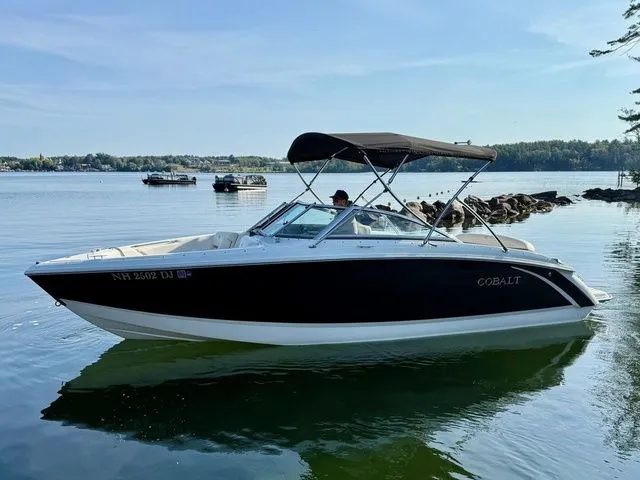 Slide: The Image of 2016 Cobalt R3 boat on calm lake with canopy, surrounded by scenic landscape. - 5