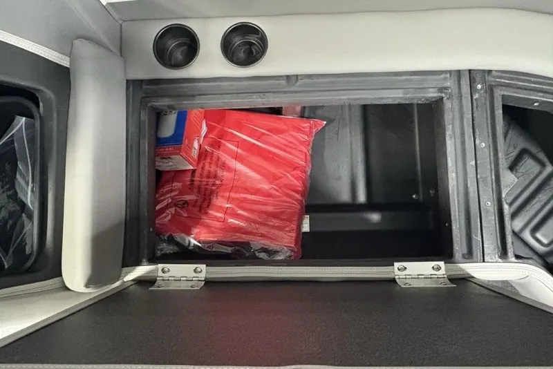 Slide: The Image of Storage compartment in 2026 Premier 220 Sunscape RF boat, containing red and blue packaged items. - 10