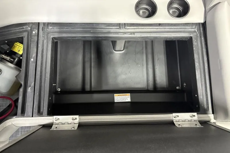 Slide: The Image of Storage compartment in 2026 Premier 220 Sunscape RF boat, featuring cup holders and warning label. - 30