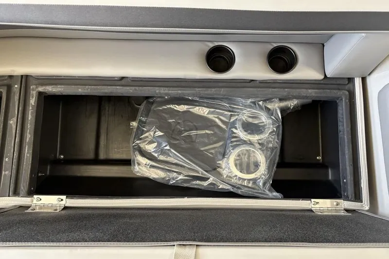 Slide: The Image of 2026 Premier 220 SUNSCAPE RL boat storage compartment with cup holders and plastic-wrapped accessories. - 8