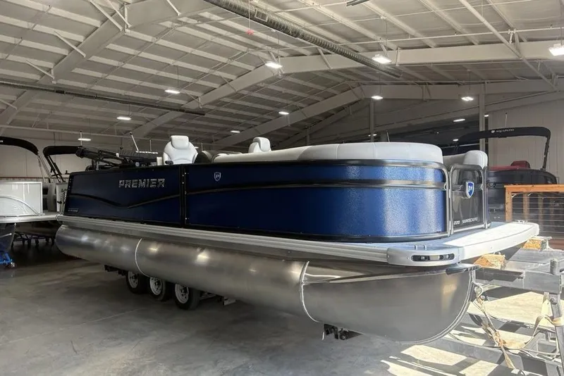Slide: The Image of 2026 Premier 220 SUNSCAPE RL pontoon boat in a spacious indoor showroom. - 2