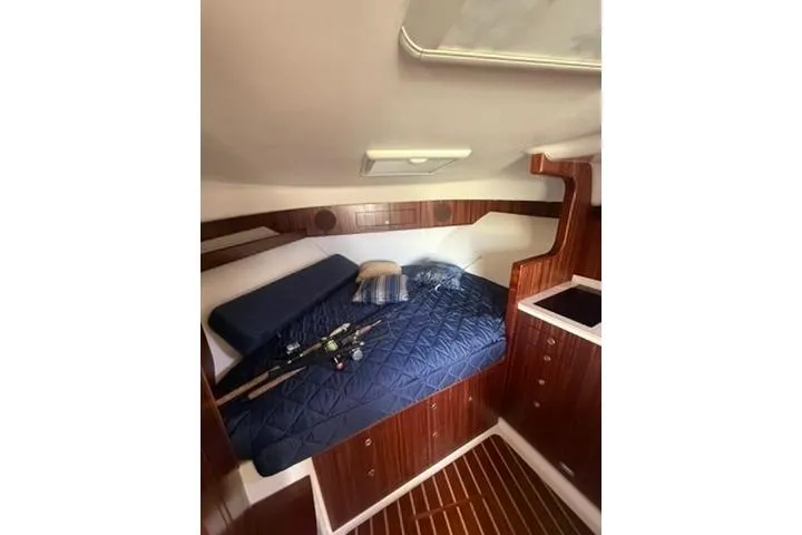 Slide: The Image of 2010 Pursuit OS 375 Offshore cabin with blue bedding and fishing rods. - 12
