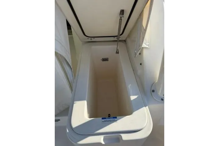 Slide: The Image of 2010 Pursuit OS 375 Offshore boat storage compartment, open lid, white interior. - 18