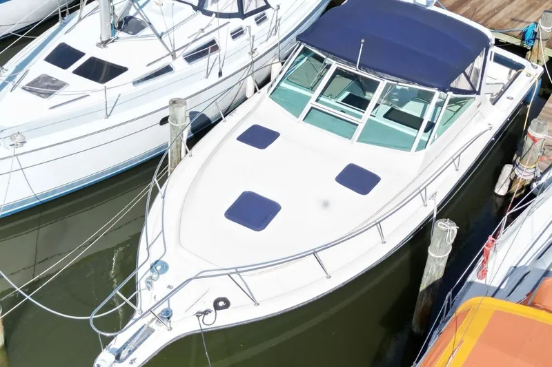 Slide: The Image of 1996 Tiara Yachts 3300 Open docked, featuring sleek design and blue canopy. - 8