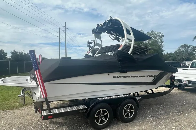 Slide: The Image of 2015 Nautique Super Air Nautique 210 boat on trailer, covered, with American flag. - 4