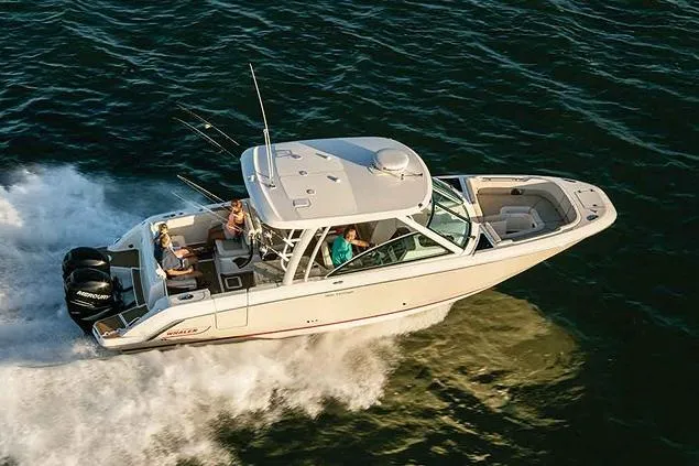 Slide: The Image of 2023 Boston Whaler 320 Vantage boat cruising on calm water near a scenic shoreline. - 1