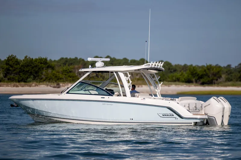 Slide: The Image of 2023 Boston Whaler 320 Vantage boat cruising on calm water near a shoreline. - 11