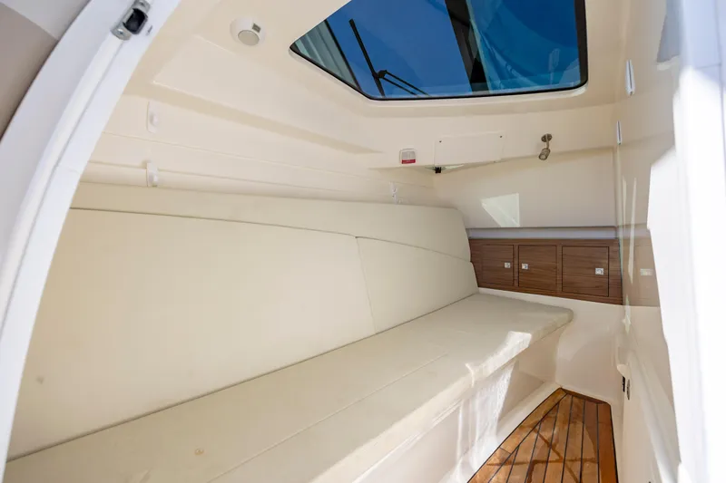 Slide: The Image of 2023 Boston Whaler 320 Vantage cabin interior with cushioned seating and wooden flooring. - 14