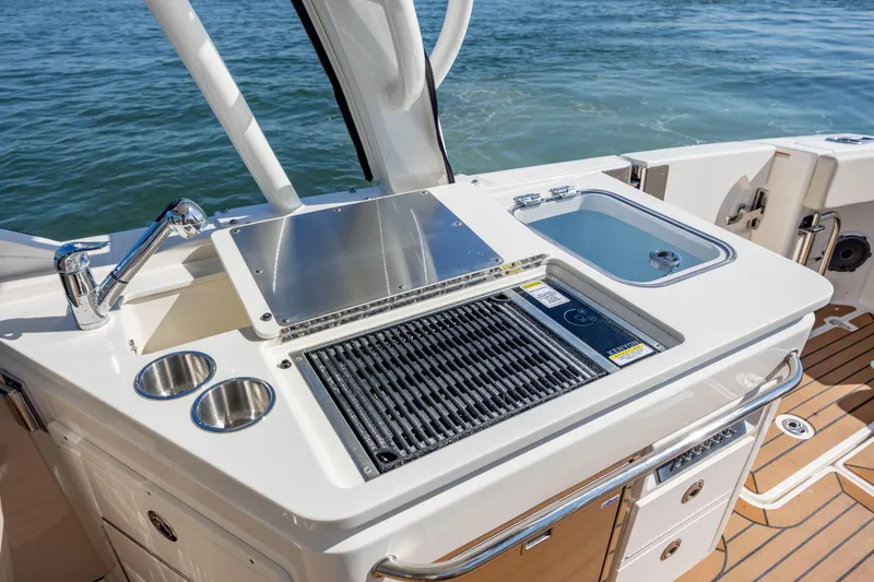 Slide: The Image of 2023 Boston Whaler 320 Vantage boat kitchen with grill and sink by the water. - 25