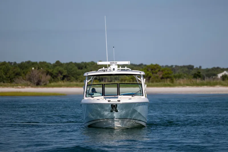 Slide: The Image of 2023 Boston Whaler 320 Vantage boat on calm water near a sandy shoreline. - 8