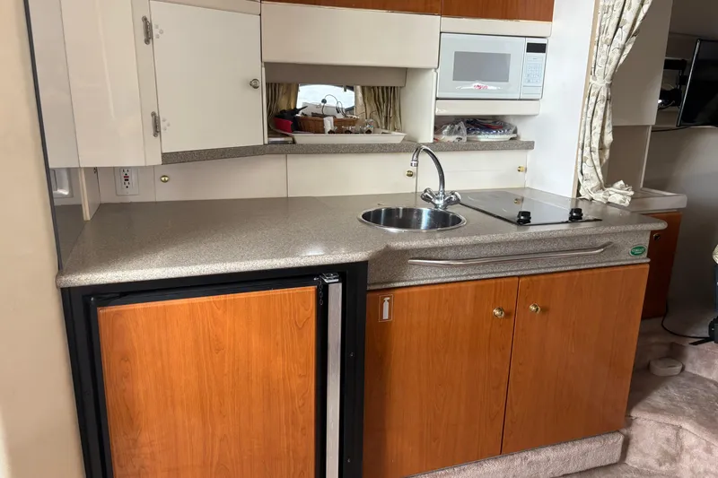 Slide: The Image of Compact kitchen area in a 2000 Formula 34 Performance Cruiser with wood cabinets and modern appliances. - 11