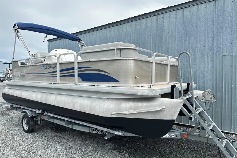 The Image of 2007 Godfrey Sweetwater Tuscany pontoon boat on trailer, blue canopy, parked by metal building. - 0