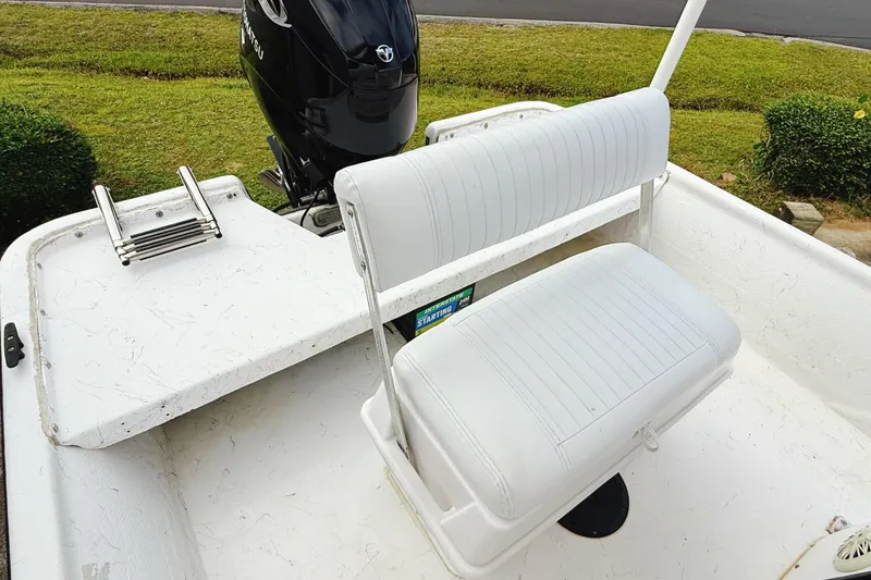 Slide: The Image of 2005 Nitro Bay boat with white seating and outboard motor, parked on grass. - 10