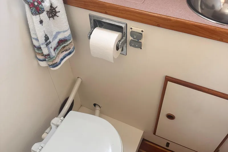 Slide: The Image of 1978 Pearson 424 boat bathroom with toilet, towel, and toilet paper holder. - 8