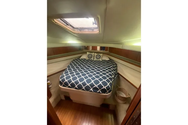 Slide: The Image of 1995 Tiara Yachts 4000 Express cabin with patterned bedding and wooden flooring. - 10