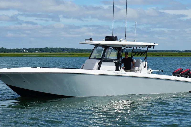 The Image of 2024 Fountain 34 TE boat cruising on a calm lake under a partly cloudy sky. - 1