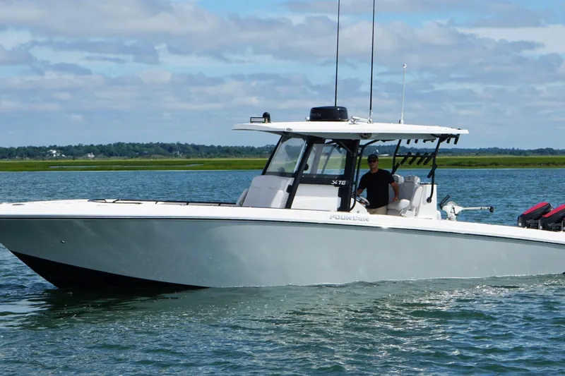 Slide: The Image of 2024 Fountain 34 TE boat cruising on a calm lake under a partly cloudy sky. - 11