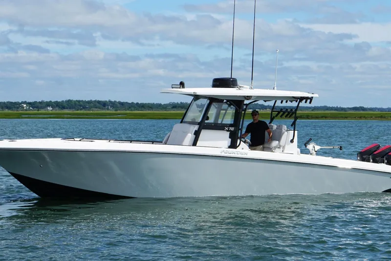 Slide: The Image of 2024 Fountain 34 TE boat cruising on a calm lake under a blue sky. - 6