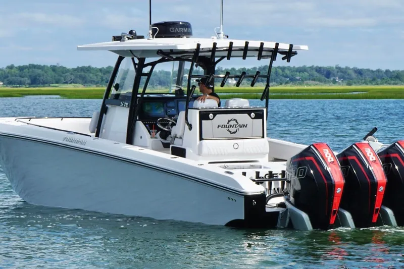 Slide: The Image of 2024 Fountain 34 TE boat with triple outboard engines on a serene waterway. - 8