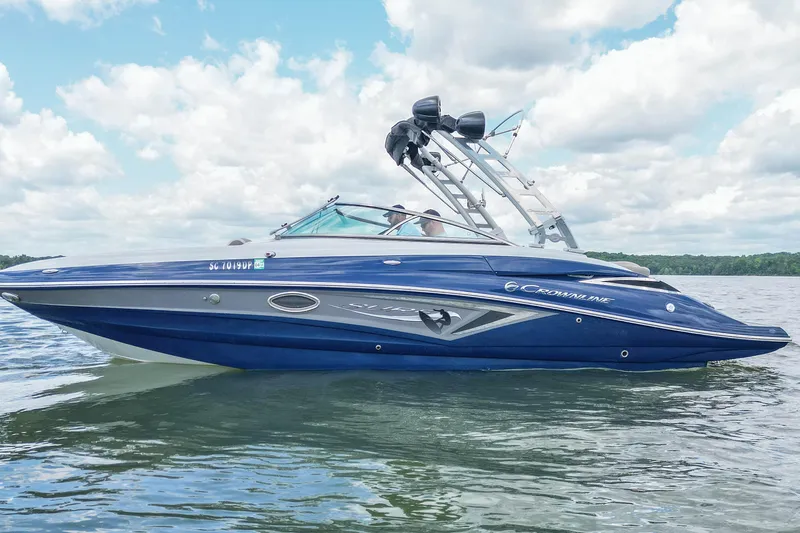 Slide: The Image of 2019 Crownline Eclipse E255 SURF boat on a calm lake under a cloudy sky. - 2