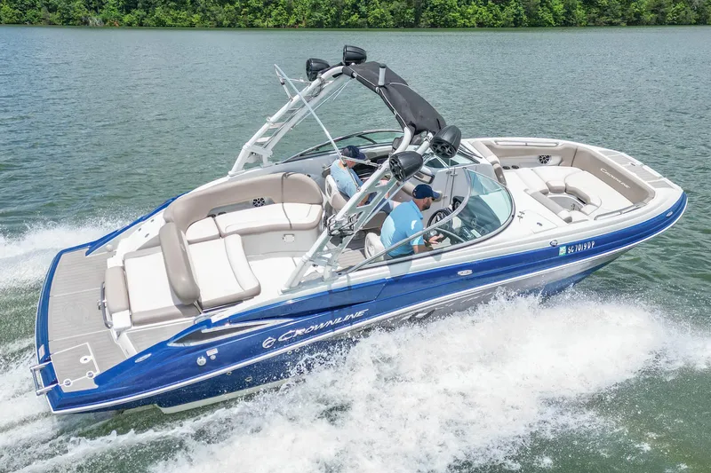 Slide: The Image of 2019 Crownline Eclipse E255 SURF boat cruising on a lake with lush green shoreline. - 6
