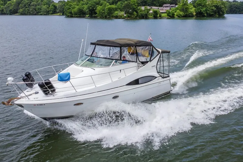 The Image of 2002 Carver 350 Mariner cruising on a scenic lake with lush green surroundings. - 0
