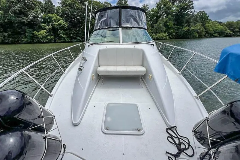 Slide: The Image of 2002 Carver 350 Mariner boat on a serene lake, featuring spacious deck and seating. - 10