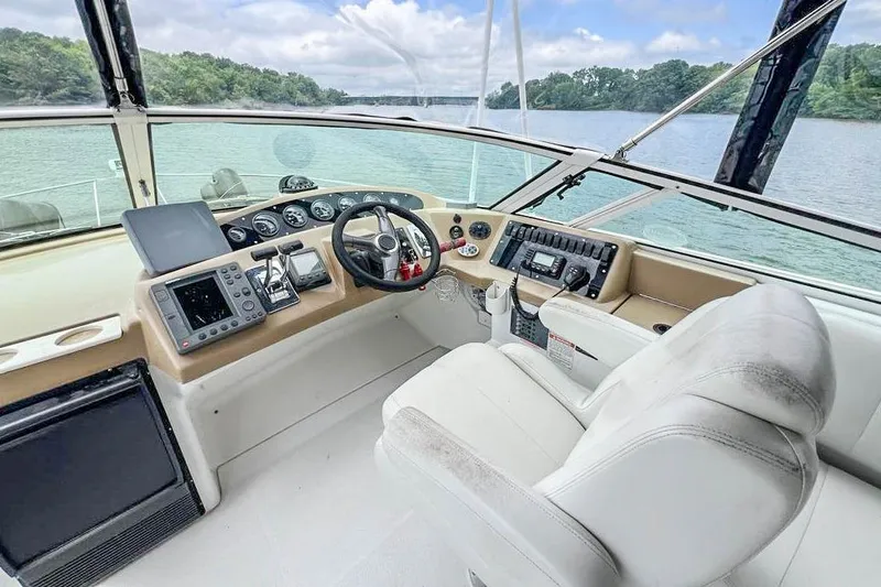 Slide: The Image of 2002 Carver 350 Mariner helm with modern controls, overlooking serene waters and lush shoreline. - 12