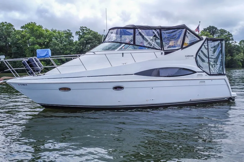 Slide: The Image of 2002 Carver 350 Mariner yacht on a calm lake with lush green trees. - 2