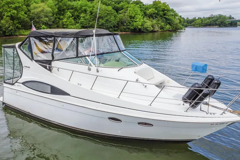 Slide: The Image of 2002 Carver 350 Mariner yacht on a serene lake with lush green shoreline. - 3