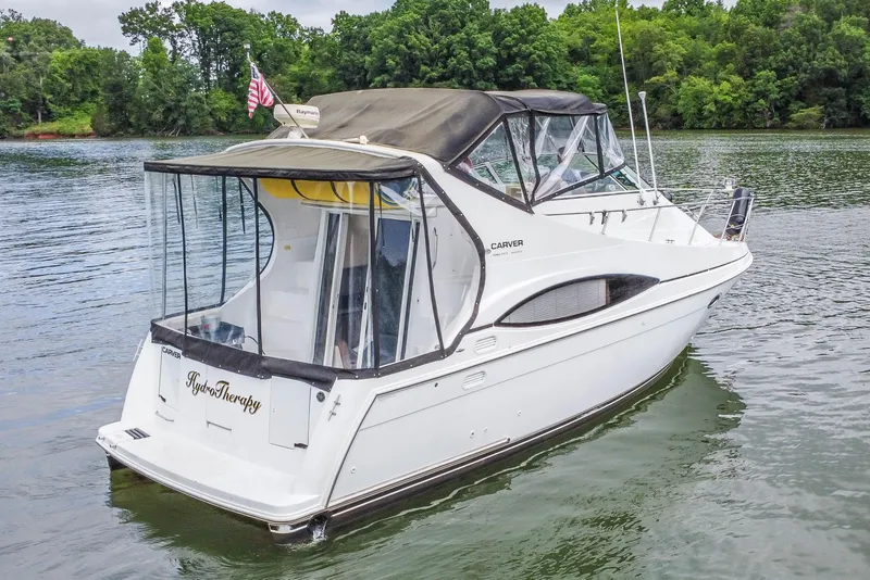Slide: The Image of 2002 Carver 350 Mariner boat on a serene lake with lush green trees. - 4