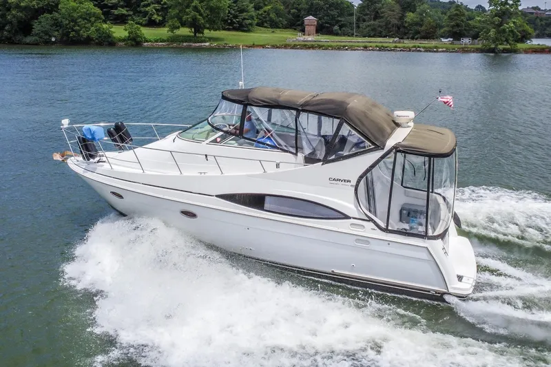 Slide: The Image of 2002 Carver 350 Mariner cruising on a scenic lake with lush green shoreline. - 6