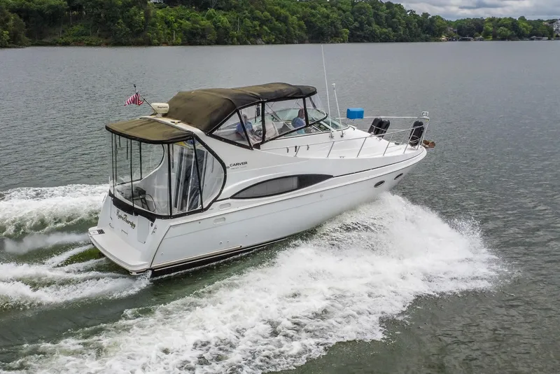 Slide: The Image of 2002 Carver 350 Mariner cruising on a lake with lush green shoreline. - 7