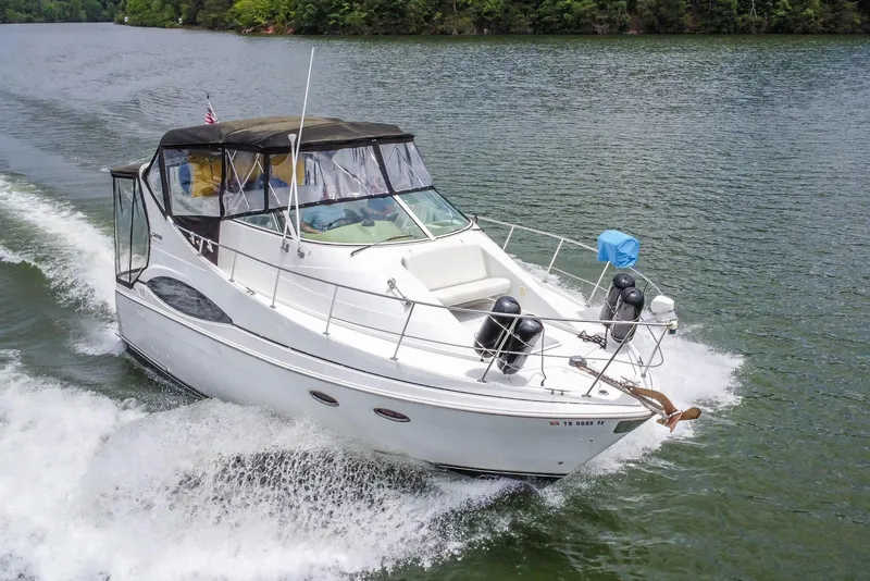 Slide: The Image of 2002 Carver 350 Mariner cruising on a scenic lake with lush green surroundings. - 8