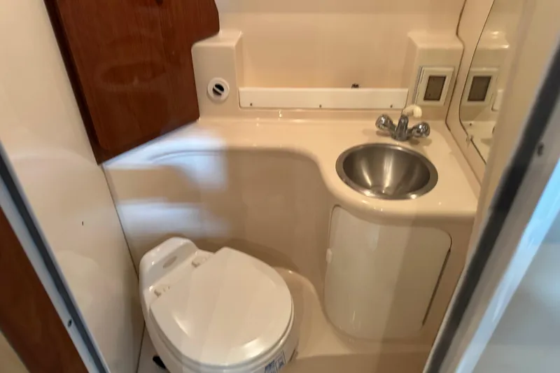 Slide: The Image of 2005 Regal Commodore 2665 boat bathroom with toilet, sink, and wooden cabinet. - 25