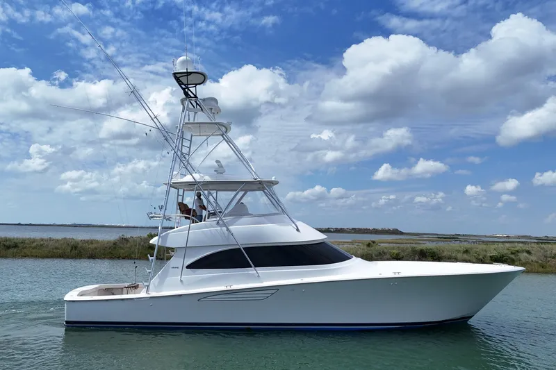 Slide: The Image of 2017 Viking 55 Convertible yacht cruising under a blue sky with clouds. - 10