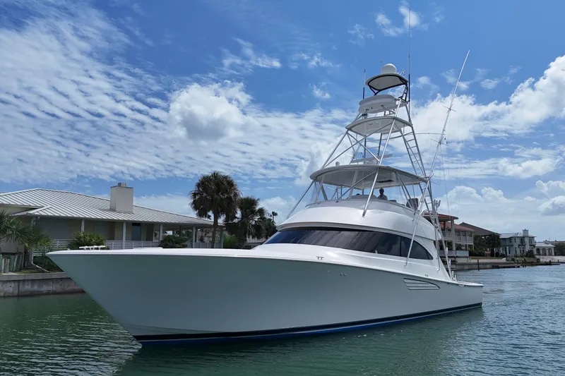 Slide: The Image of 2017 Viking 55 Convertible yacht cruising near waterfront homes under a blue sky. - 11