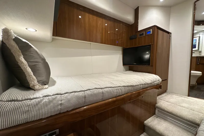 Slide: The Image of 2017 Viking 55 Convertible yacht interior with cozy bed, TV, and wooden cabinetry. - 110