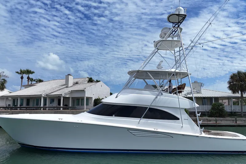Slide: The Image of 2017 Viking 55 Convertible yacht docked near waterfront homes under a blue sky. - 12