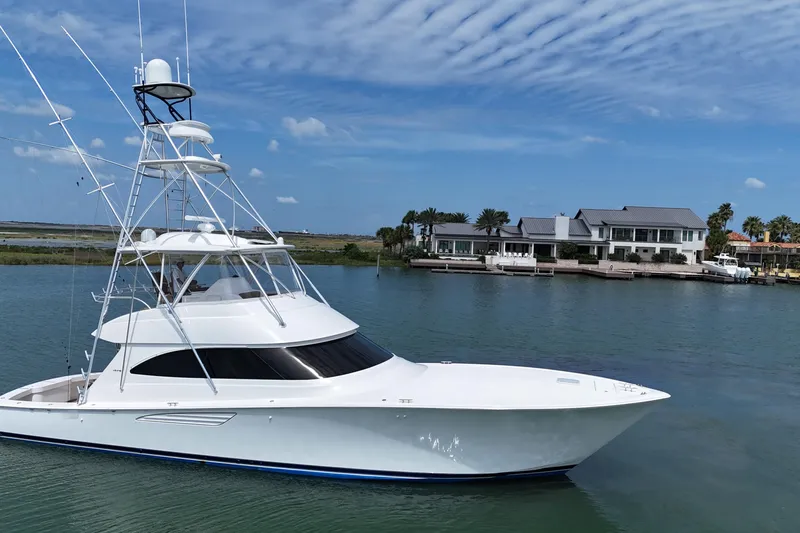 Slide: The Image of 2017 Viking 55 Convertible yacht cruising near waterfront homes under a blue sky. - 17