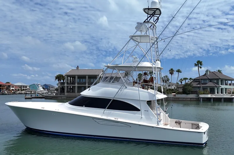 Slide: The Image of 2017 Viking 55 Convertible yacht docked near waterfront homes under a blue sky. - 27