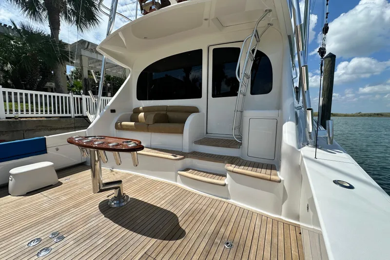 Slide: The Image of 2017 Viking 55 Convertible yacht with teak deck and seating area, docked by water. - 53