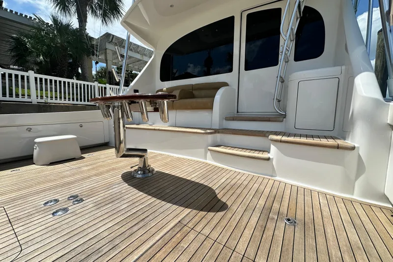 Slide: The Image of 2017 Viking 55 Convertible yacht deck with seating and ladder, featuring teak flooring. - 56