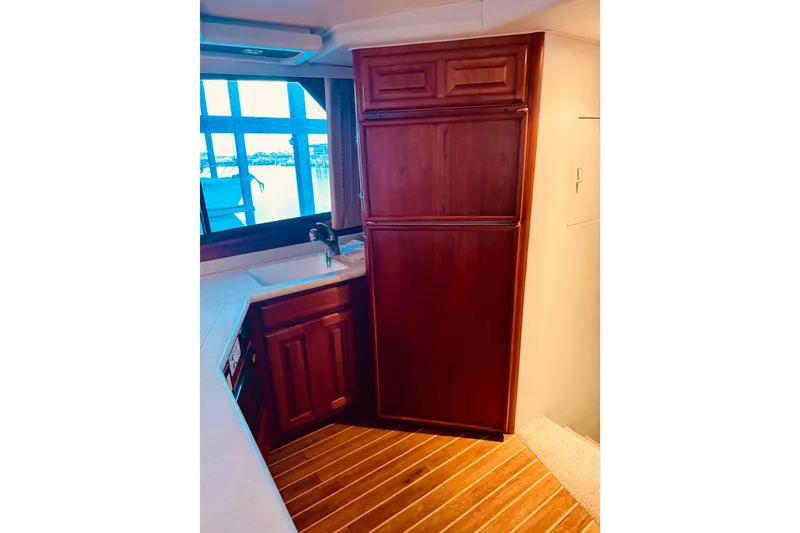 Slide: The Image of 1993 Viking 50 Convertible yacht kitchen with wooden cabinets and window view. - 28